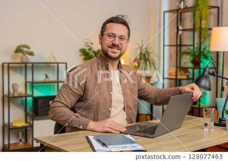 Caucasian young businessman opening laptop and working on project sitting at home office table desk 128077463