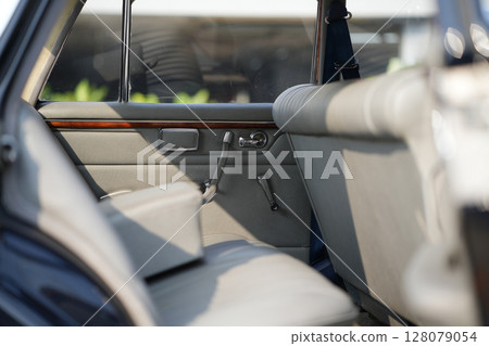 The inner door handles of a vintage car are captured in a clean view, reflecting the classic design and preserved components that represent the simplicity and authenticity of vintage cars. 128079054