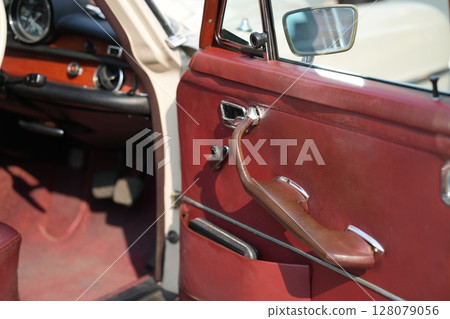 The inner door handles of a vintage car are captured in a clean view, reflecting the classic design and preserved components that represent the simplicity and authenticity of vintage cars. The inner door handles of a vintage car are captured in a clean view, reflecting the classic design and preserved components that represent the simplicity and authenticity of vintage cars. 128079056