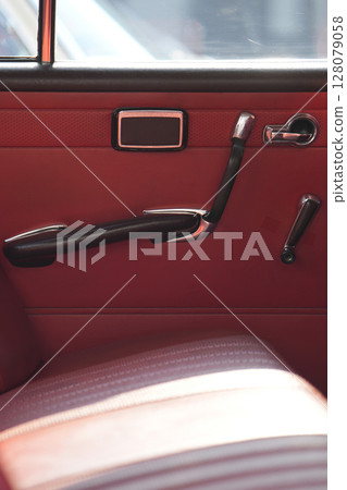 The inner door handles of a vintage car are captured in a clean view, reflecting the classic design and preserved components that represent the simplicity and authenticity of vintage cars. 128079058