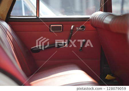 The inner door handles of a vintage car are captured in a clean view, reflecting the classic design and preserved components that represent the simplicity and authenticity of vintage cars. 128079059