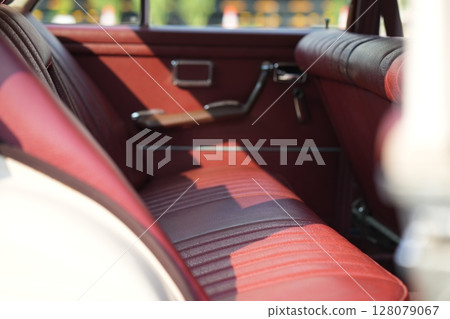 Leather rear seats of a vintage classic car mid-20th century automotive craftsmanship, with textured surfaces, comfort and retro aesthetics. 128079067