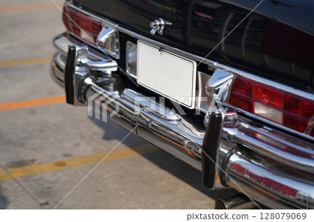 The position and mounting of license plates on classic cars, showing standard rear placement with chrome surroundings. These plates are blank, suitable for graphic mockups or editorial use. 128079069