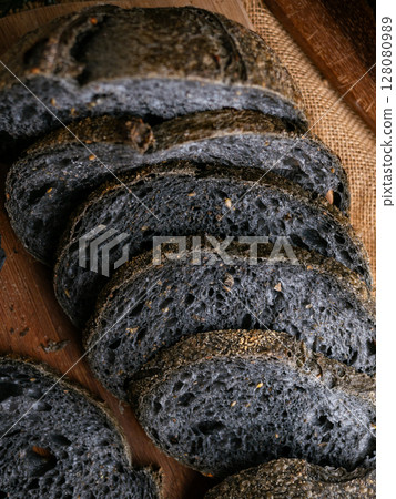 Fresh baked black charcoal sourdough ciabatta bread sliced on wooden board. Fresh baked black charcoal sourdough ciabatta bread sliced on wooden board. 128080989