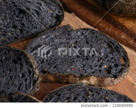 Fresh baked black charcoal sourdough ciabatta bread sliced on wooden board. Fresh baked black charcoal sourdough ciabatta bread sliced on wooden board. 128080990