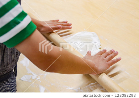 Child rolling out buckwheat dough with a rolling pin (7-year-old boy) 128082298