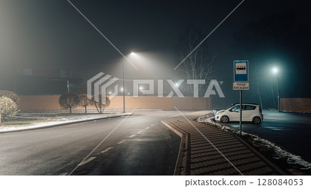 Foggy Night Bus Stop with Lone Car and Streetlights 128084053