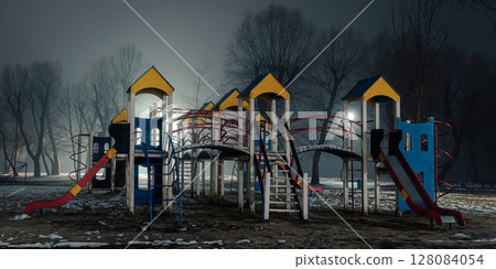 Empty children's playground at night, illuminated by soft streetlights. Empty children's playground at night, illuminated by soft streetlights. 128084054