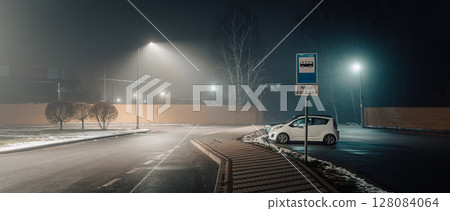 Foggy Night Bus Stop with Lone Car and Streetlights Foggy Night Bus Stop with Lone Car and Streetlights 128084064