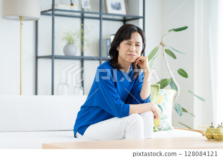 A middle-aged housewife worried in the living room 128084121