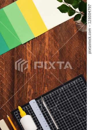 Workspace for paper crafts. Black cutting mat, colored paper, pencils, scissors, ruler, glue. Space for your text. 128084797