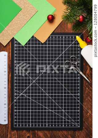 Workspace for paper crafts. Black cutting mat, colored paper, pencils, scissors, ruler, glue. Space for your text. 128084799