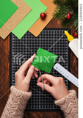 Let's make a simple paper craft. A bookmark in the shape of a Christmas tree. Use scissors to cut notches along the sides of the triangle. 128084803