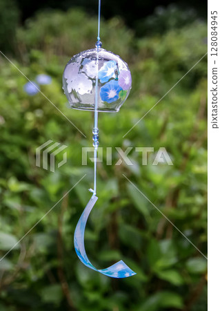 A glass wind chime decorated with a morning glory motif, with a hydrangea field in the background 128084945