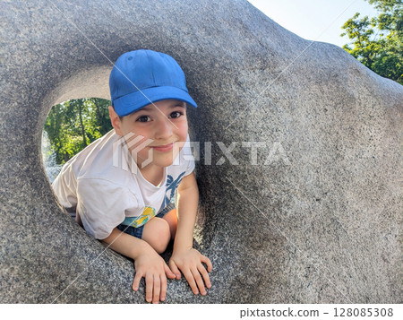 Little boy playing among decorative stones in summer park, space for text 128085308