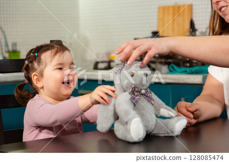 Woman encouraging toddler's imagination through play at kitchen table. Concept of preschool learning, emotional development, and creativity 128085474