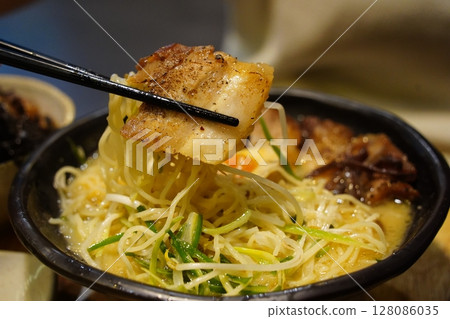 Close-up of Japanese Ramen Noodles with Pork Belly Lifted by Chopsticks Close-up of Japanese Ramen Noodles with Pork Belly Lifted by Chopsticks 128086035