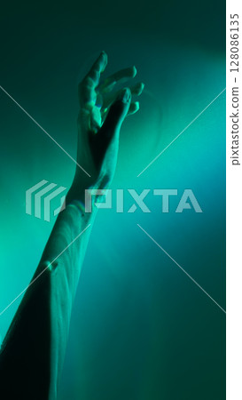A Captivating Visual Exploration of an Outstretched Hand Bathed in Ethereal Green Light Symbolizing Connection and Expression Through Art 128086135
