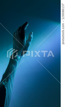 A Mesmerizing Exploration of Light and Shadow: A Hand Reaching Out Towards a Soft Blue Glow Evokes Wonder and Intrigue in the Depths of the Visual Experience A Mesmerizing Exploration of Light and Shadow: A Hand Reaching Out Towards a Soft Blue Glow Evokes Wonder and Intrigue in the Depths of the Visual Experience 128086137