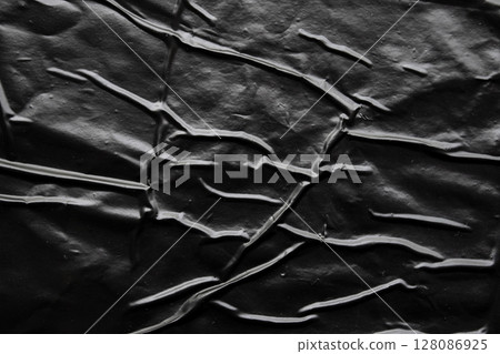 black crumpled and creased plastic poster texture background 128086925