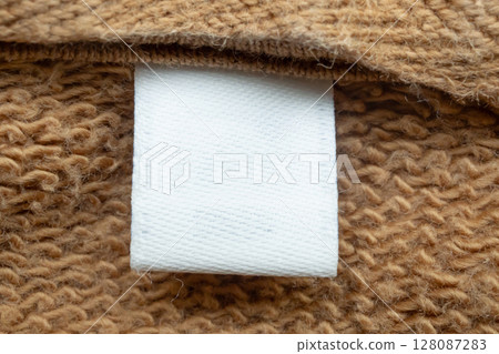 White blank laundry care clothes label on brown shirt fabric background 128087283