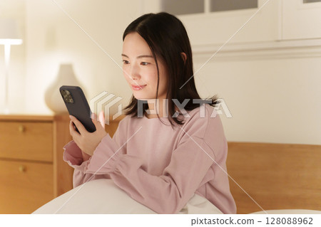 A woman looking at her smartphone in the middle of the night A woman looking at her smartphone in the middle of the night 128088962