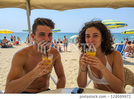couple drinking champagne on beach 128089972