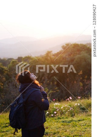 Asian young woman backpack smiling and standing with wildflower and beautiful landscape of valley Doi Luang Chiang Dao mountain, Chiang Mai Province of Thailand 128090427