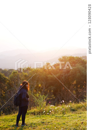Asian young woman backpack smiling and standing with wildflower and beautiful landscape of valley Doi Luang Chiang Dao mountain, Chiang Mai Province of Thailand 128090428