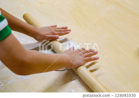 Child rolling out buckwheat dough with a rolling pin (7-year-old boy) Child rolling out buckwheat dough with a rolling pin (7-year-old boy) 128091030