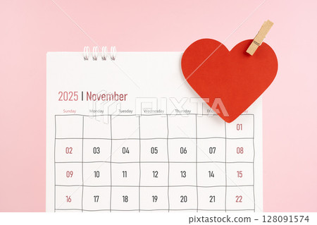November 2025 desk calendar with red heart note on pink color background. November 2025 desk calendar with red heart note on pink color background. 128091574
