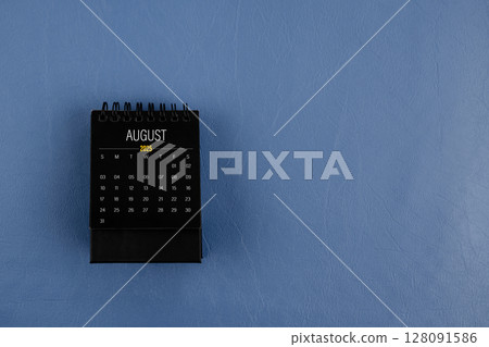 August 2025 black desk calendar on navy blue color leather background. August 2025 black desk calendar on navy blue color leather background. 128091586