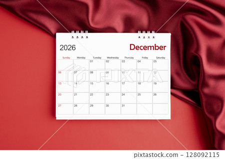 Top view of December 2026 desk calendar on red silk color background. 128092115