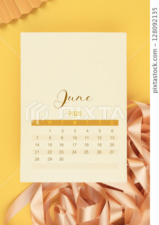 June 2026 calendar page with yellow ribbon on yellow background. 128092135