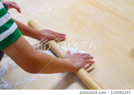 Child rolling out buckwheat dough with a rolling pin (7-year-old boy) Child rolling out buckwheat dough with a rolling pin (7-year-old boy) 128092245