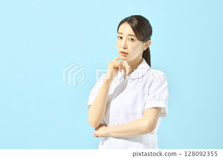 A nurse in a white coat standing in front of a blue background 128092355