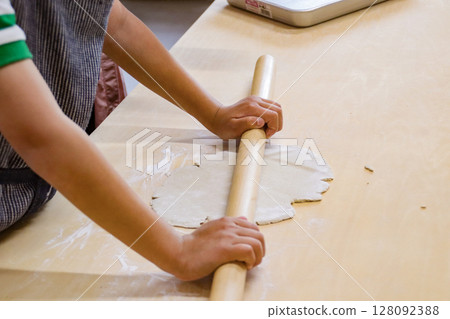 Child rolling out buckwheat dough with a rolling pin (7-year-old boy) 128092388