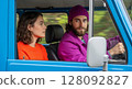 Young couple driving a vintage blue car enjoying a road trip adventure 128092827