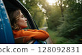 Young woman enjoying road trip looking out of car window in forest 128092831