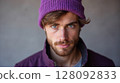 Portrait of confident young man wearing purple beanie and jacket 128092833