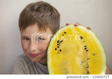 The boy is holding a large yellow watermelon.Child with fruit. The boy is holding a large yellow watermelon.Child with fruit. 128093577