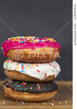 Lovely sweet food. Stack of glazed colorful assorted donuts with splashes on a gray background. 128093652