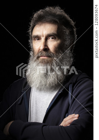 Portrait of an elderly man with a gray beard on a black background. 128093674