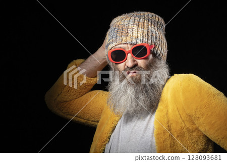 Creative elderly man with a gray beard in fashionable clothes on a black background. 128093681