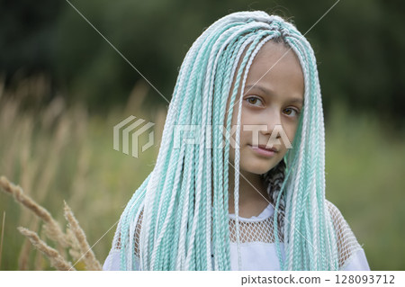Fashionable little girl with multicolored African braids looks into the camera. 128093712