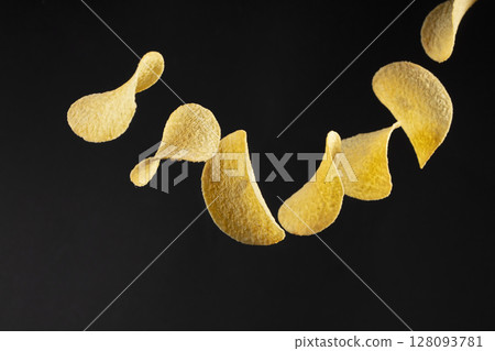 Chips on a black background. Flying potato chips. Chips on a black background. Flying potato chips. 128093781