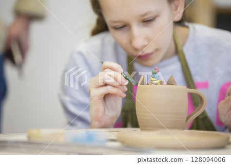 Clay modeling master class. A teenage girl sculpts a cup from clay. 128094006