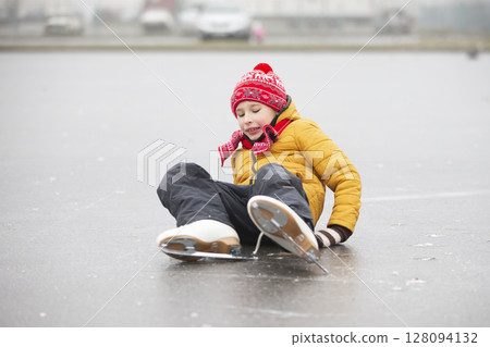 A little boy fell when he was learning to skate.A child on an ice rink. A little boy fell when he was learning to skate.A child on an ice rink. 128094132