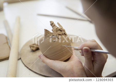 Clay modeling workshop. A girl sculpts a cup from clay. 128094303