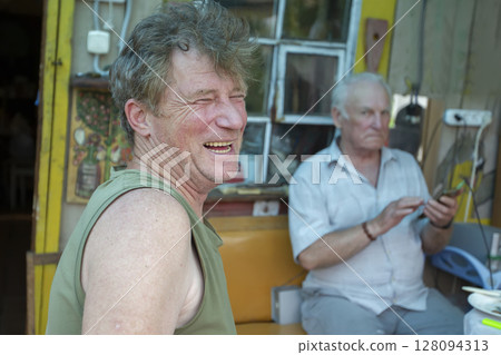An adult son laughs merrily against the background of an elderly old man's father. Father and son. An adult son laughs merrily against the background of an elderly old man's father. Father and son. 128094313